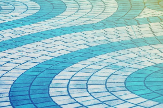 Curved blue and white paving tiles forming an abstract wave pattern on a walkway.